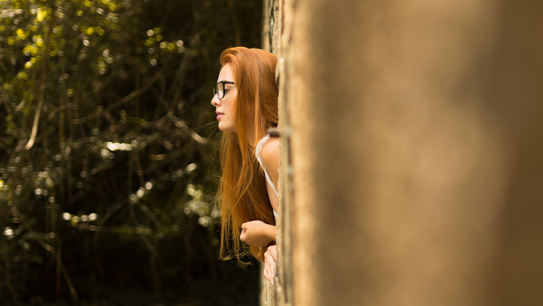 selective focus photo of woman with half her body leaning out of a window